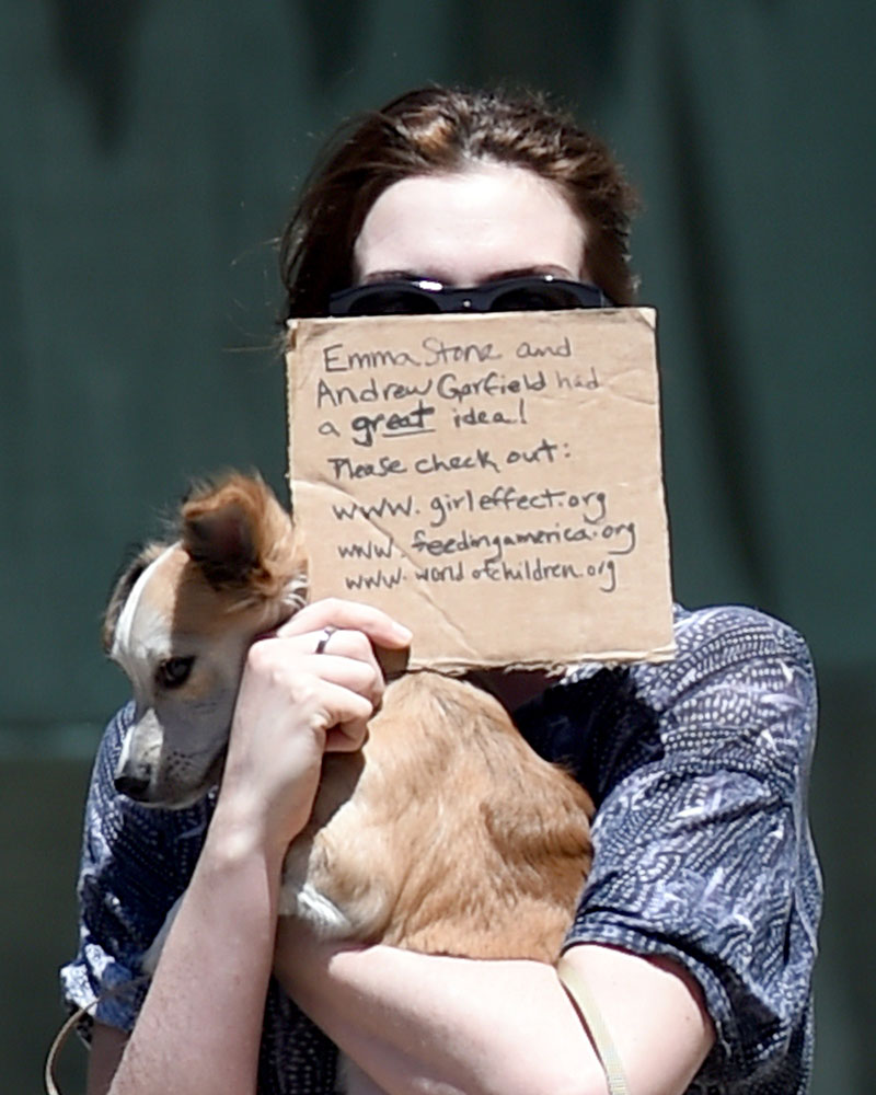EXCLUSIVE: Anne Hathaway and Adam Shulman hold signs in front of their faces on a beautiful day in Brooklyn, NY