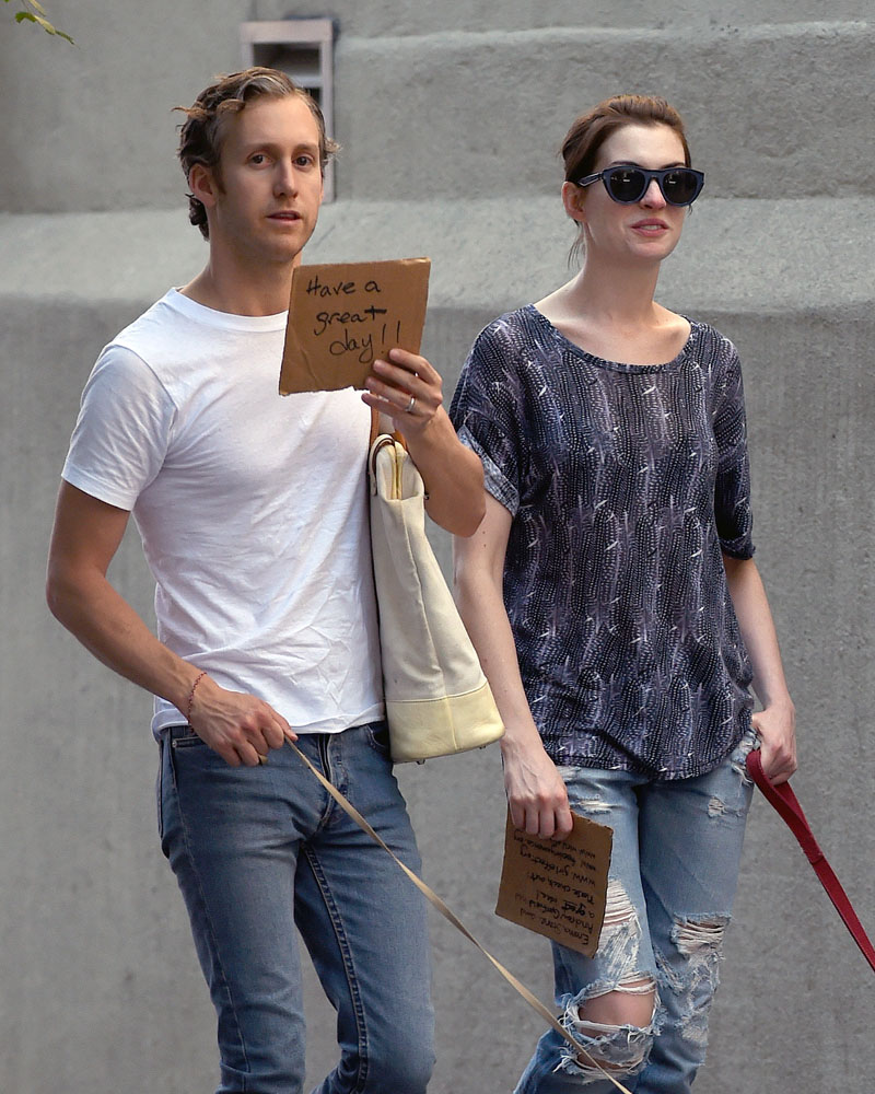 EXCLUSIVE: Anne Hathaway and Adam Shulman hold signs in front of their faces on a beautiful day in Brooklyn, NY