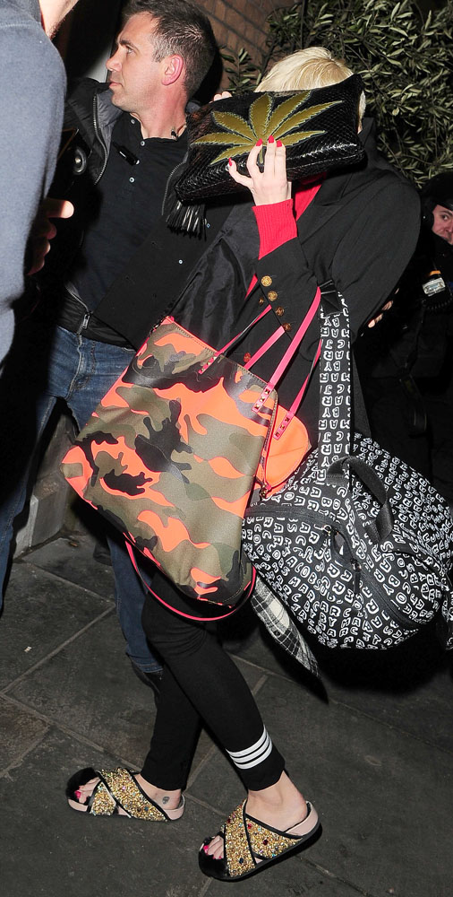Miley Cyrus covers her face with a cannabis leaf clutch bag